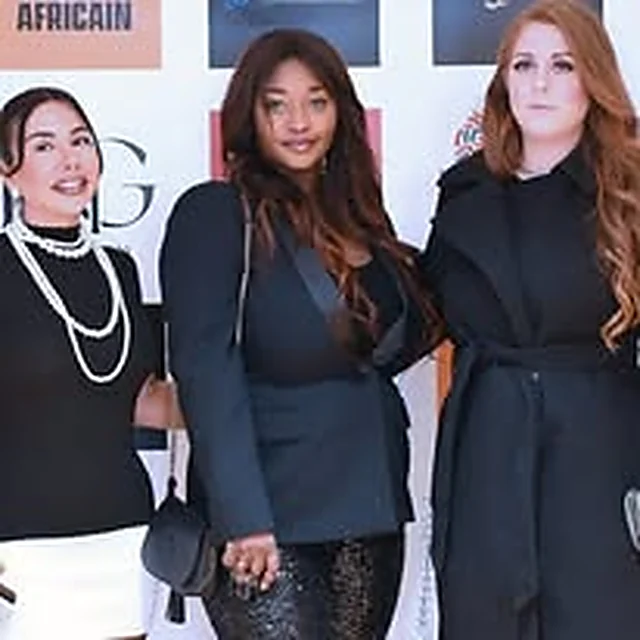 Trois invitées devant le mur des partenaires à l’Afro Gala 2024, aux Terrasses du Parc à Villeurbanne